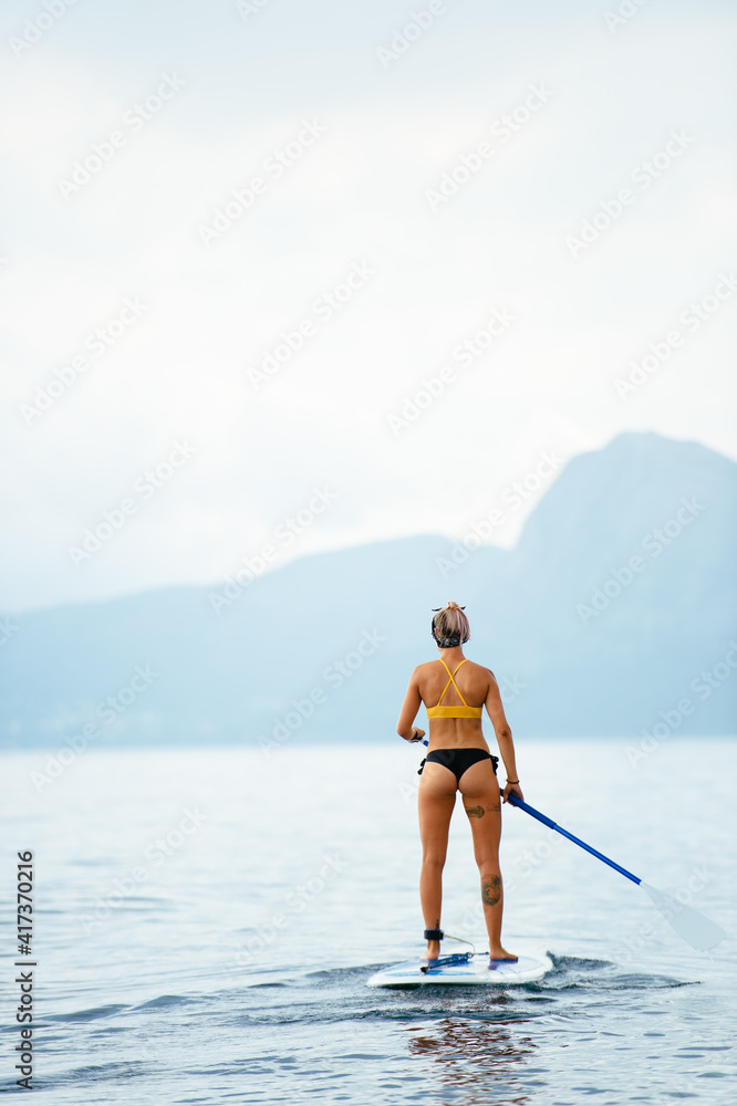 Sporty woman on glanders surfboard at sea