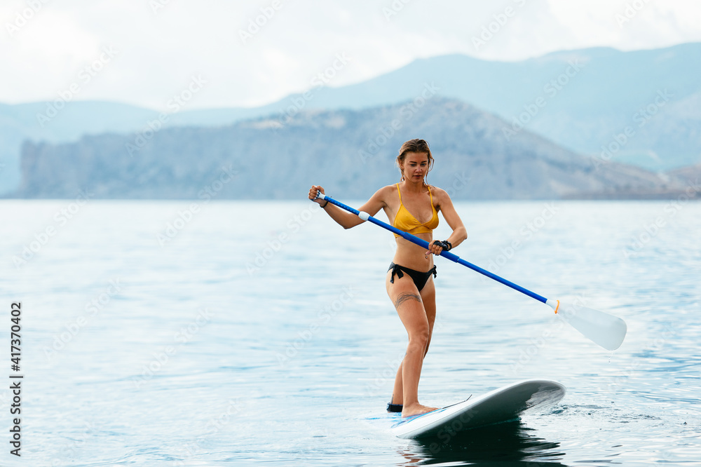 Sporty woman on glanders surfboard at sea Sporty woman on glanders surfboard at sea