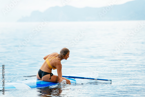 Sporty woman on glanders surfboard at sea photo