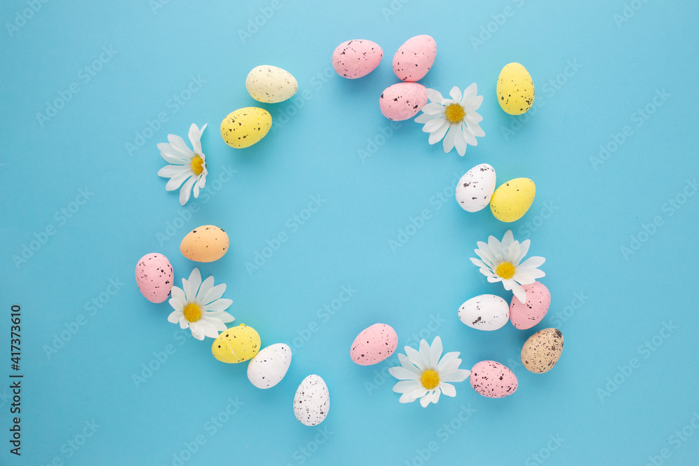 Easter invitation with eggs and daisies on a blue background with copyspace Easter invitation with eggs and daisies on a blue background with copyspace
