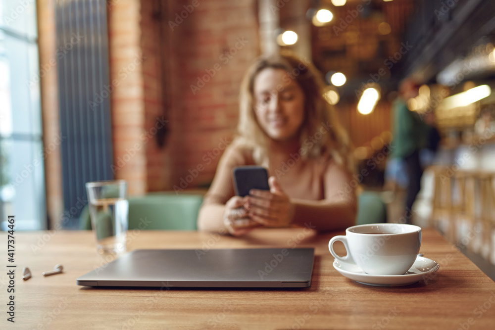 Woman sitting at cafe and using smartphone Woman sitting at cafe and using smartphone