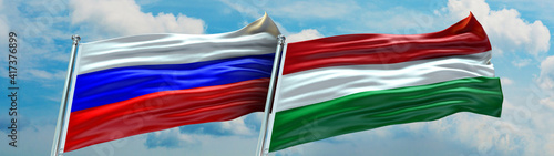 Hungar Flag and Russia Flag waving with texture in Blue sky and clouds Double flag photo