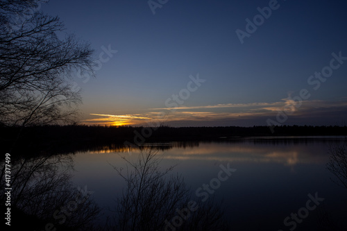 Dramatic and colorful sunset over a forest lake reflected in the water. Blakheide  Beerse  Belgium. High quality photo