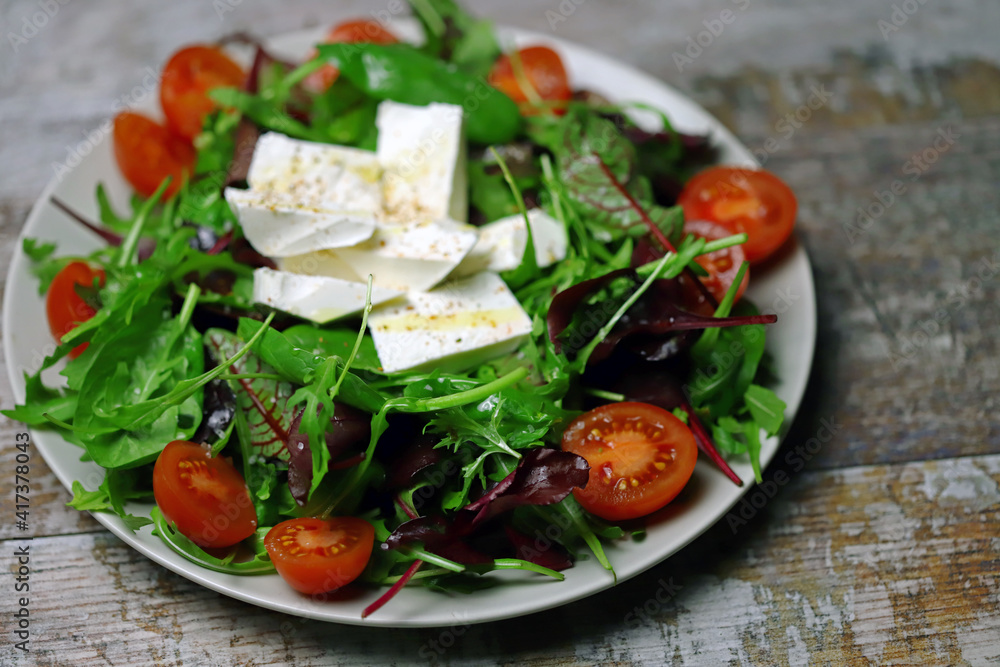 Delicious salad with feta cheese and cherry tomatoes. Healthy diet. A plate of salad. Spring food. Delicious salad with feta cheese and cherry tomatoes. Healthy diet. A plate of salad. Spring food.