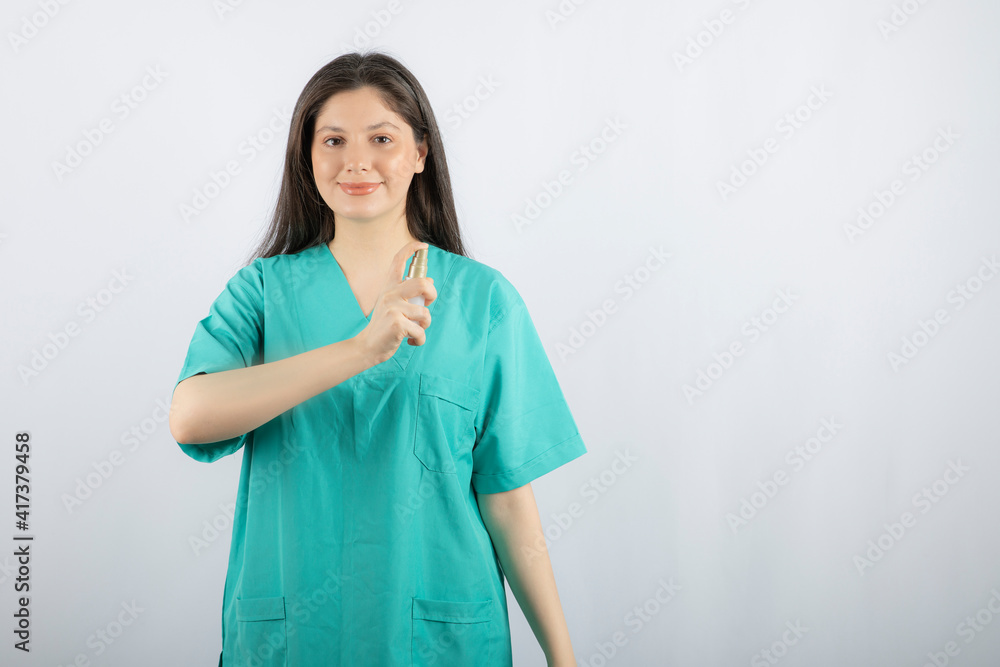 Smiling female nurse showing spray bottle on white background Smiling female nurse showing spray bottle on white background