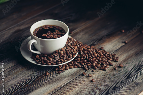 saucer with coffee beans and white cup on a wooden table side view Copy Space
