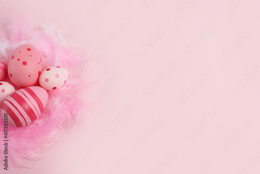 Pink eggs with feathers on pink background, copy space
