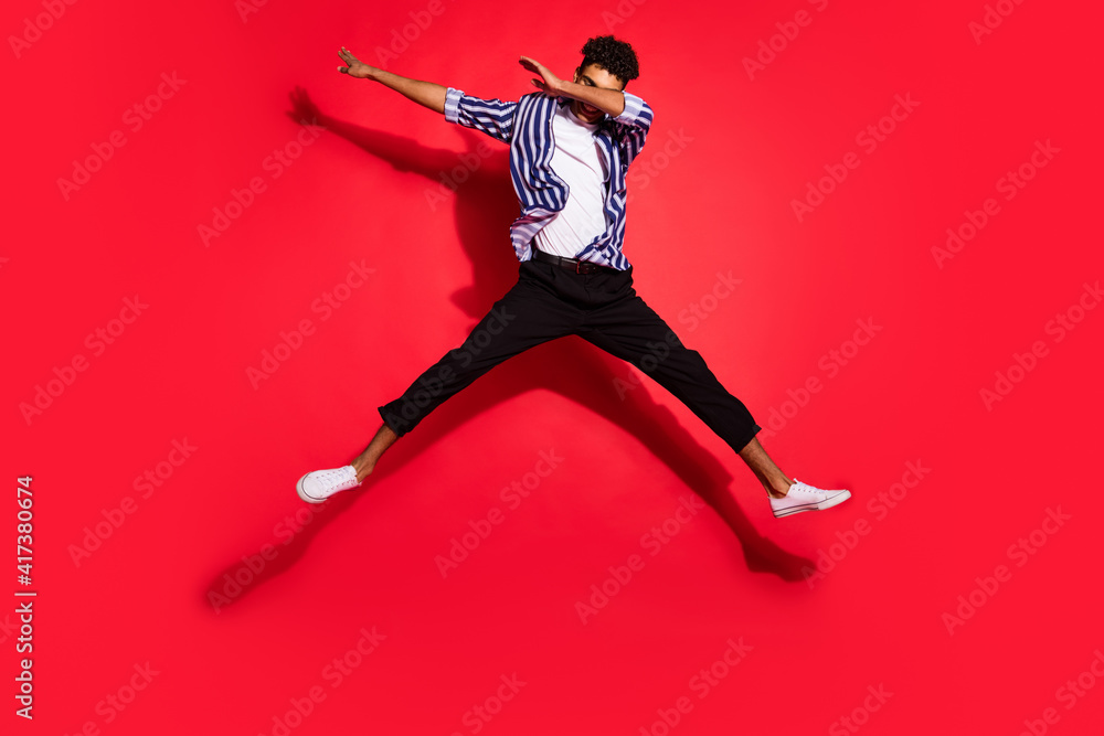 Full length photo of young handsome black man jump up pose dab active isolated over red color background