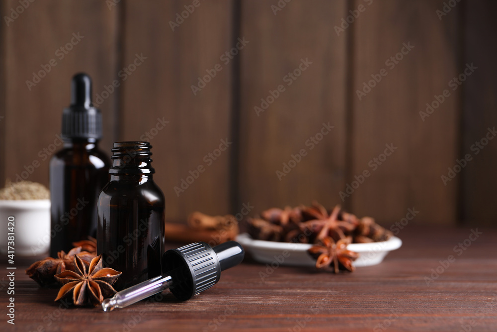 Anise essential oil and spice on wooden table, space for text