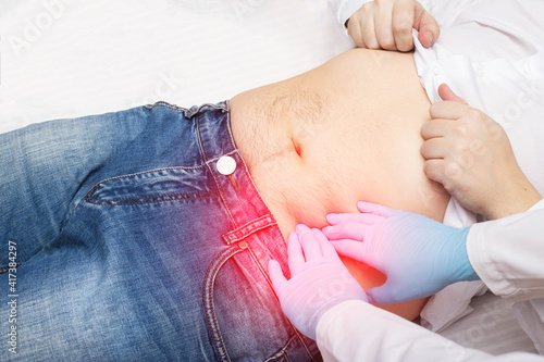 The doctor, with the help of palpation, examines the abdomen of the patient who has pain and rumbling. Bowel disease concept, sigmoiditis. photo