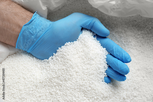 Foto Person in gloves taking pellets of ammonium nitrate from bag, closeup