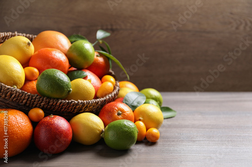 Different citrus fruits on wooden table. Space for text