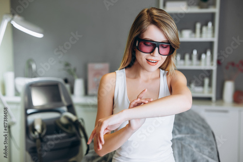 Woman smiling and looks happy before getting laser treatment on her body lying on medical table in a beauty salon