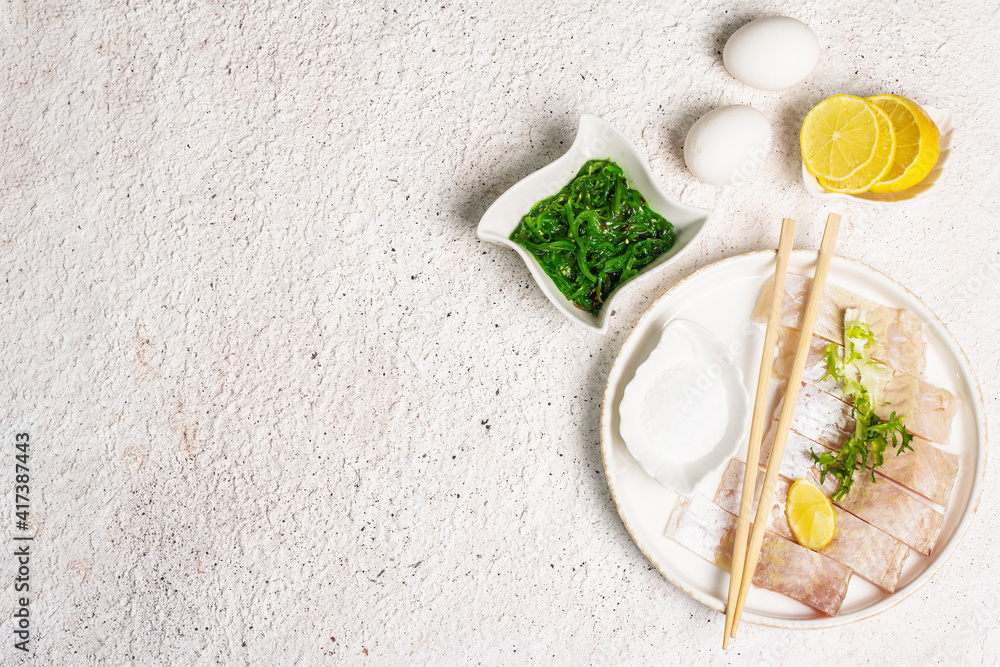 Pieces of raw hake, chukka salad, lemon wedge, fresh herbs, eggs as food preparation concept Pieces of raw hake, chukka salad, lemon wedge, fresh herbs, eggs as food preparation concept