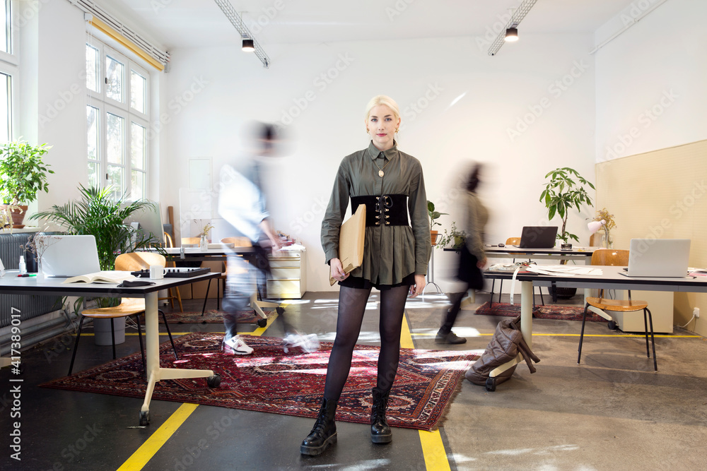 Young woman standing in busy creative co-working space Young woman standing in busy creative co-working space