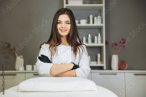 Consultation in cosmetology clinic. Female beauty doctor in white coat and black gloves crossed hands. Healthcare concept. photo