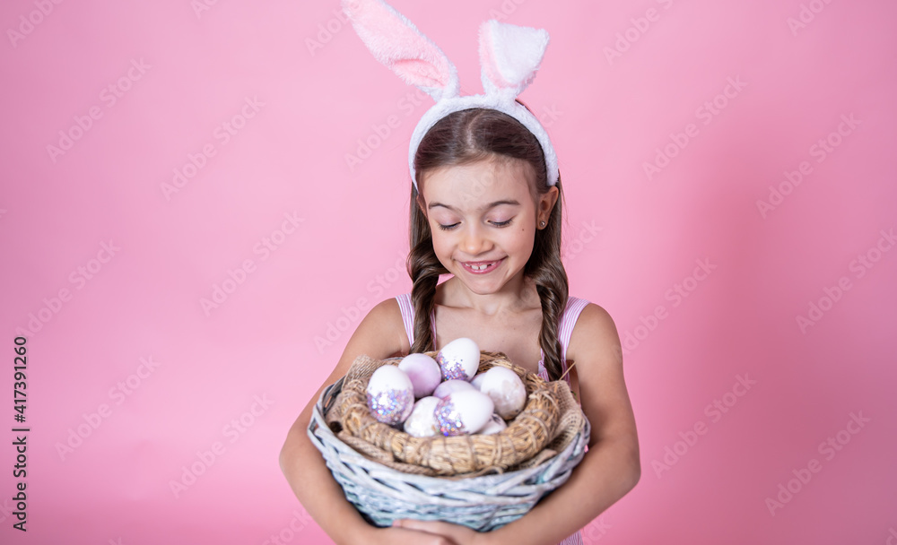 A cute little girl dressed in Easter bunny ears and in a dress posing with a basket of Easter eggs. A cute little girl dressed in Easter bunny ears and in a dress posing with a basket of Easter eggs.