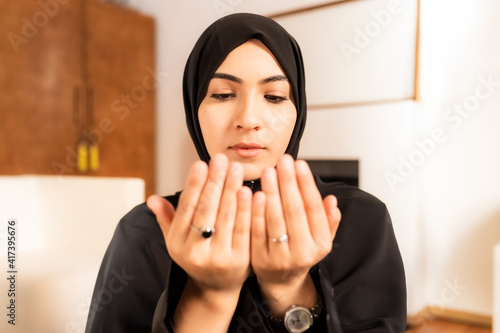 Young muslim woman with hands together during prayer photo