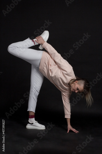 Woman blonde jumps on a black background in a light pink bike, jeans and crowns, Sport and Health concept