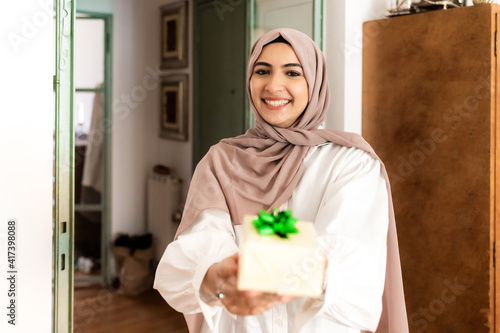 Young muslim woman giving a gift photo