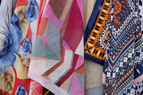 Colorful textile scarves on fabric market, background texture