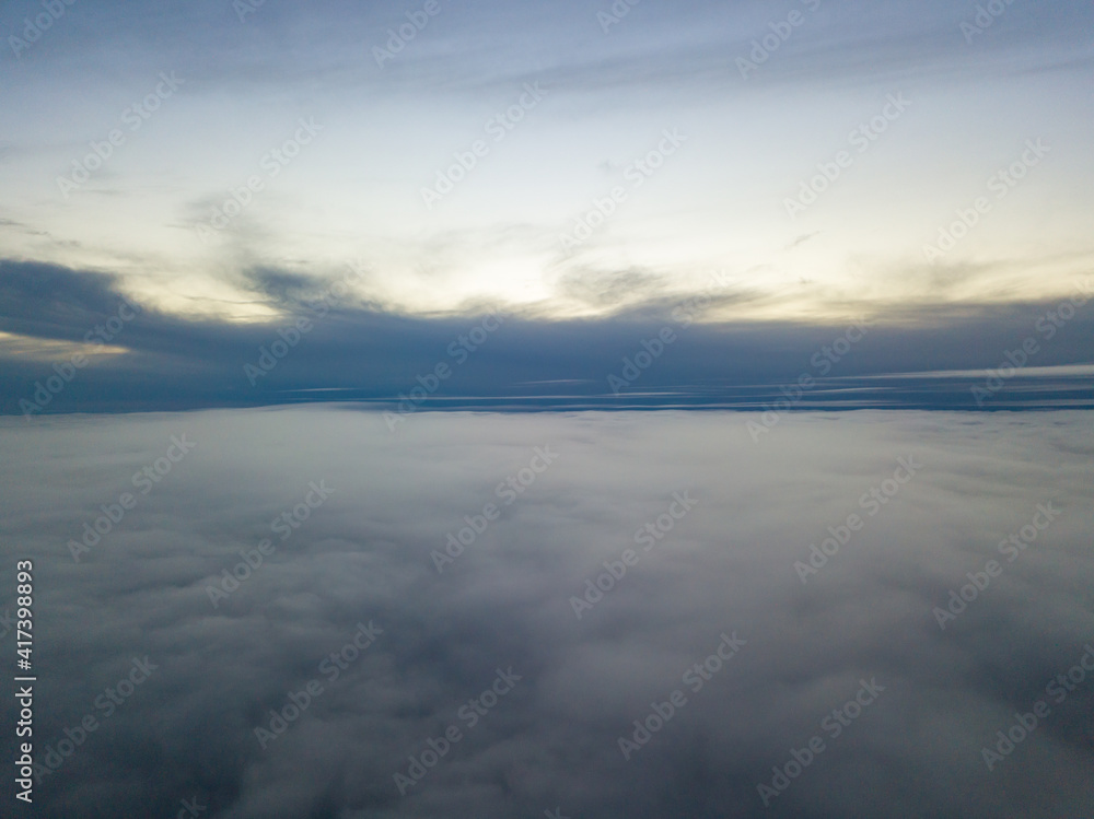 High flight above the clouds at sunset. Aerial view.