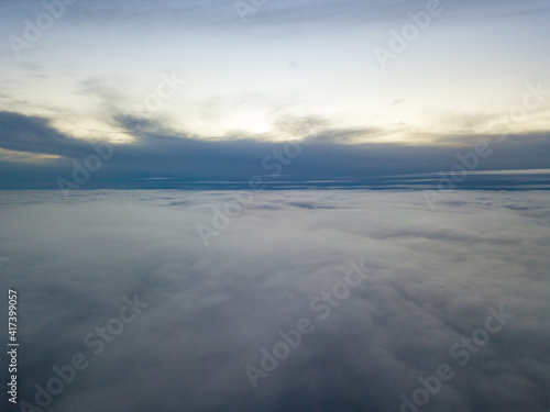 High flight above the clouds at sunset. Aerial view.