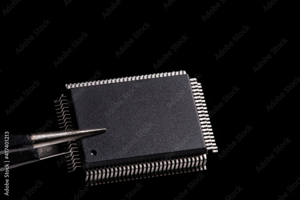 Close-up photos, IC microchip in tweezers on black background. Close-up photos, IC microchip in tweezers on black background.