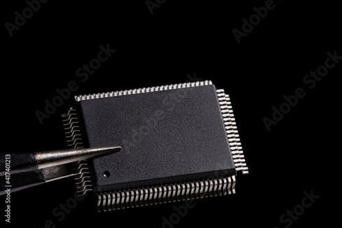 Fotografie Close-up photos, IC microchip in tweezers on black background.