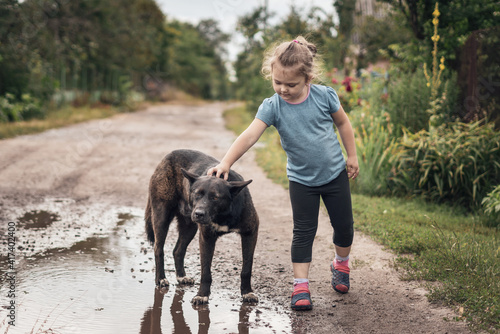 Little girl stroking a big black stray dog in the street © andrei310