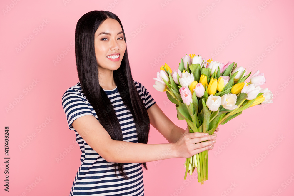 Photo portrait of asian girl giving tulips bunch on birthday smiling cheerful wearing casual dress isolated on pastel pink color background Photo portrait of asian girl giving tulips bunch on birthday smiling cheerful wearing casual dress isolated on pastel pink color background