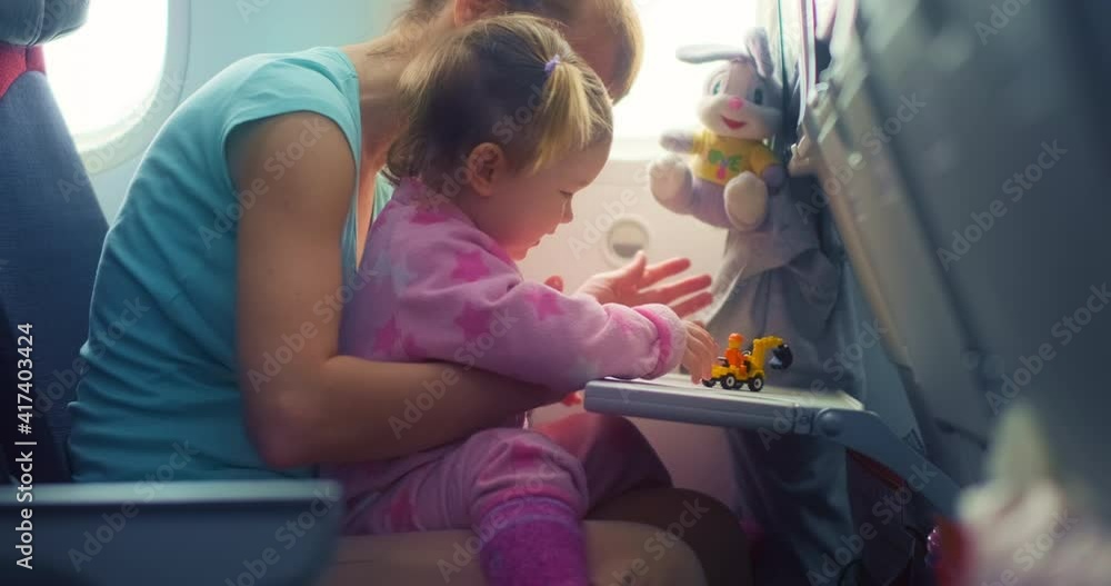 Flight in airplane with baby. Mother entertains her kid with toys during flight on aircraft Flight in airplane with baby. Mother entertains her kid with toys during flight on aircraft