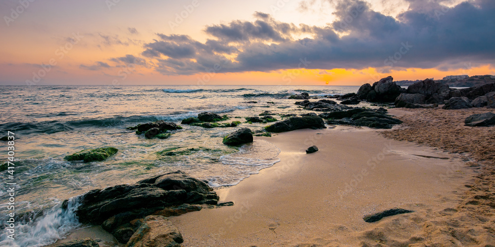 sea landscape at dawn. rocks on the sandy beach. clouds on the sky. summer vacation concept