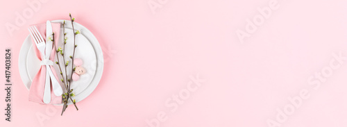 Easter holiday table setting on a pink paper background.Plates with colorful eggs. Easter holiday concept .Top view, copy space.Banner