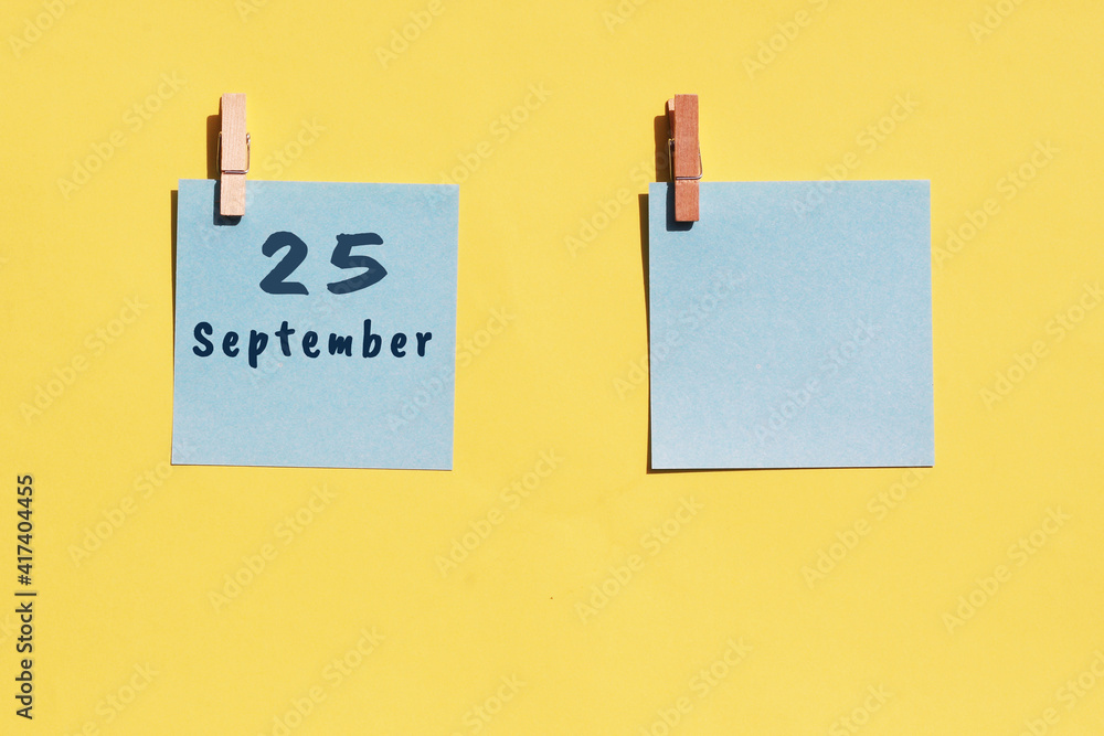 25 september. 25th day of the month, calendar date. Two blue sheets for writing on a yellow background. Top view, copy space. Autumn month, day of the year concept 25 september. 25th day of the month, calendar date. Two blue sheets for writing on a yellow background. Top view, copy space. Autumn month, day of the year concept