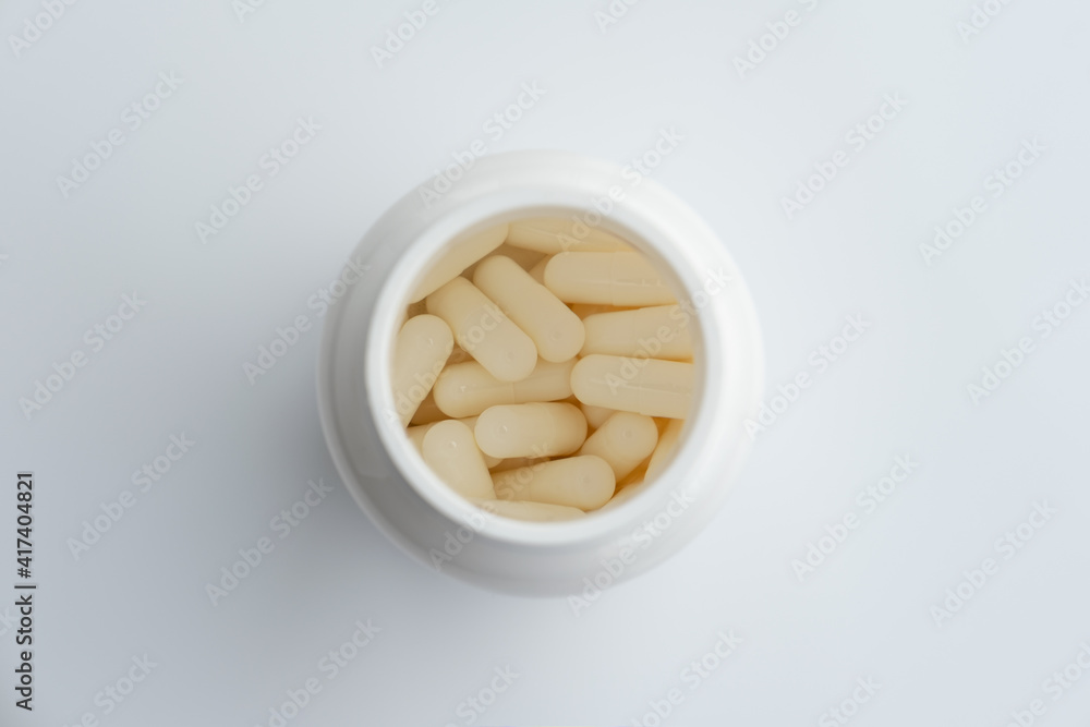 white plastic medicine vial can jar with capsules on white background, with a blur white plastic medicine vial can jar with capsules on white background, with a blur