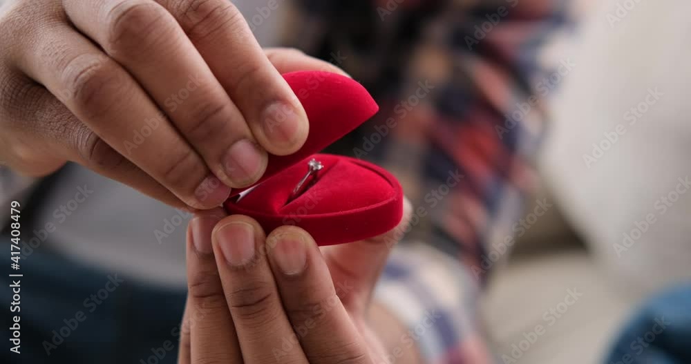 Man holding red gift box with engagement ring at home Man holding red gift box with engagement ring at home
