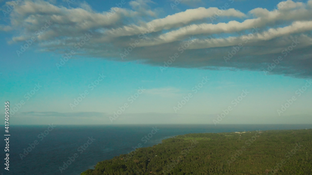 Beautiful skyscape with white clouds over the coast of the island and the blue sea, aerial view. Seascape: Ocean and sky.Philippines, Camiguin.