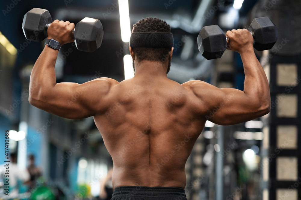 Back view of african american shirtless man exercising at gym Back view of african american shirtless man exercising at gym
