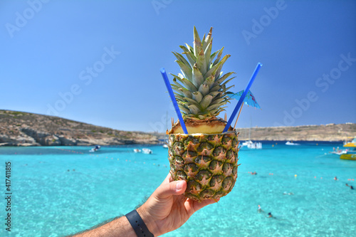 Pineapple cocktail drink over Blue Lagoon sea waters on Comino island photo