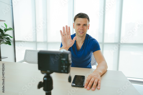 Young man waving hand while presenting live streaming to followers