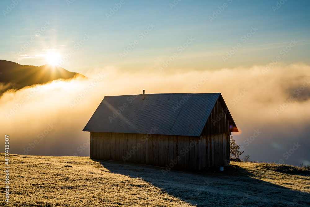 A lonely house stands in a clearing against the backdrop of a beautiful sky and white fog A lonely house stands in a clearing against the backdrop of a beautiful sky and white fog