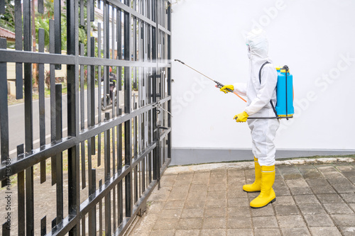 Disinfectant service worker spraying fence