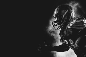 American football player. Sportsman with ball in helmet on stadium in action.