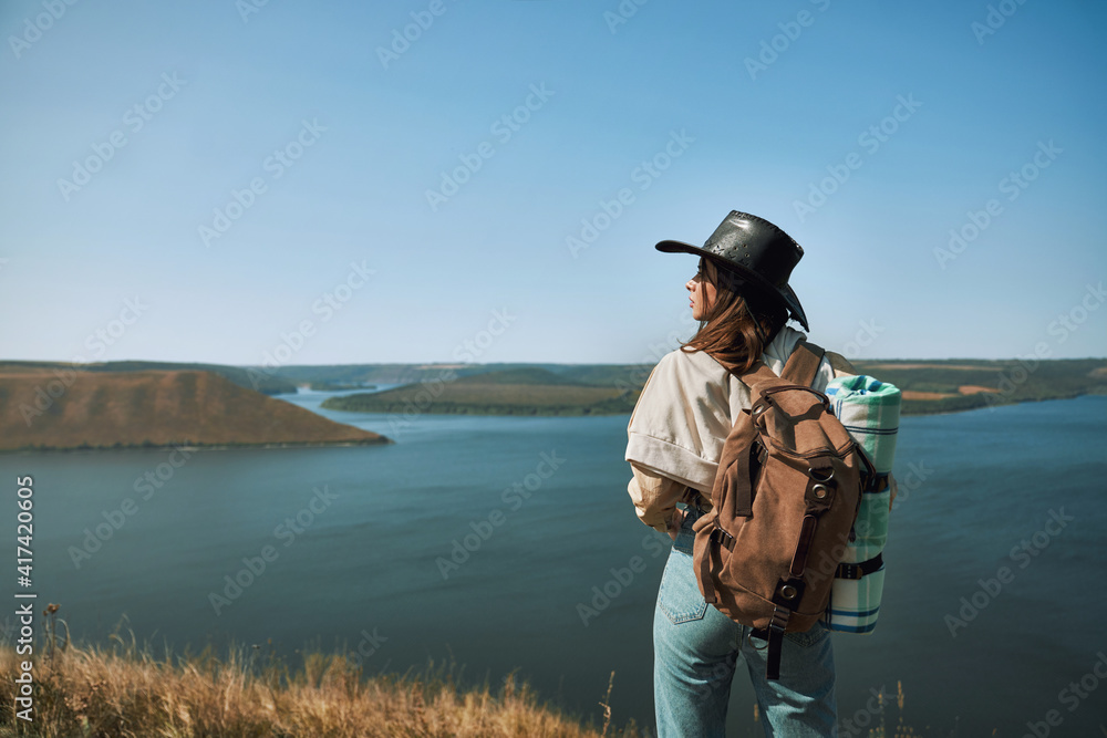 Woman with backpack standing on top of hill Woman with backpack standing on top of hill