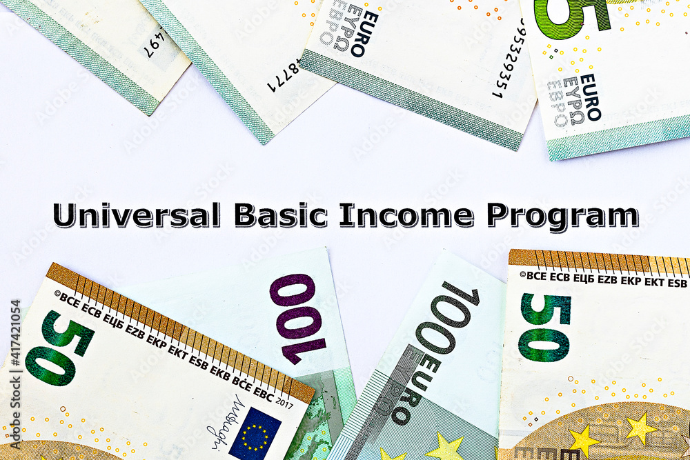 Topview photo on Universal Basic Income theme. The words Universal Basic Income program on paper, surrounded by euro banknotes Topview photo on Universal Basic Income theme. The words Universal Basic Income program on paper, surrounded by euro banknotes
