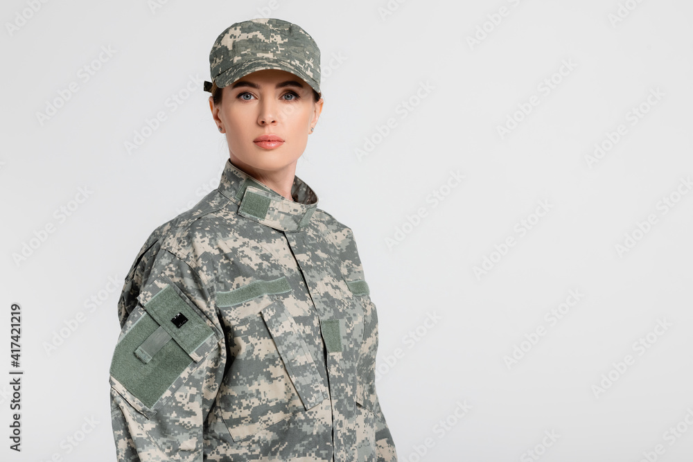 Soldier in military uniform and cap looking at camera isolated on grey Soldier in military uniform and cap looking at camera isolated on grey