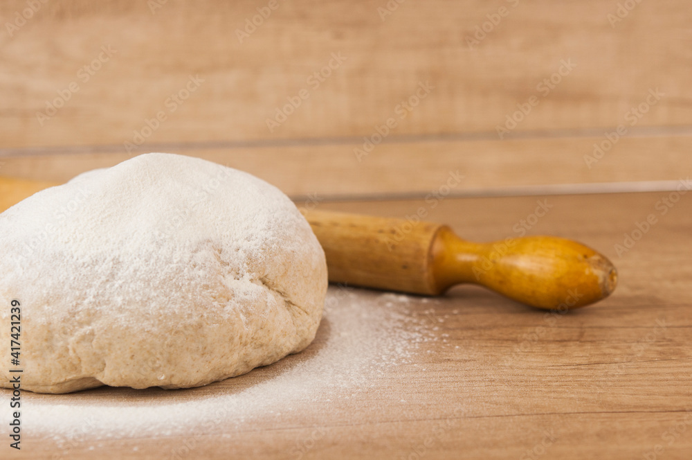 homemade pizza dough with rolling pin on the wooden table homemade pizza dough with rolling pin on the wooden table