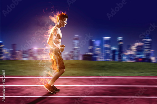 Male athlete running fast as fire flame on track