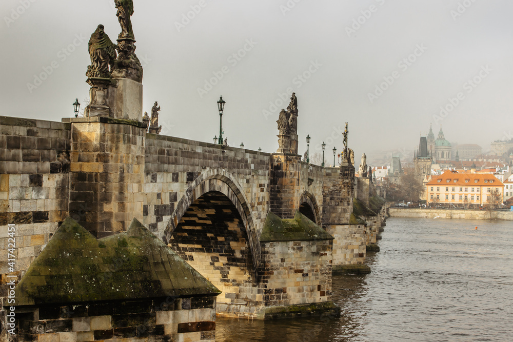 Postcard view of Charles Bridge and Lesser Town in mist,Czech republic.Famous tourist destination.Prague panorama.Foggy morning in city.Amazing European cityscape.Romantic atmosphere travel background